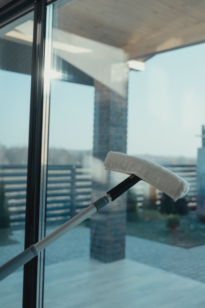 A contemporary cleaning device designed to wash a large glass window overlooking a clear outdoor scene.
